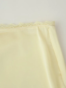 Vue macro détaillée du tissu satiné jaune pâle avec bordure en dentelle sur le vêtement
