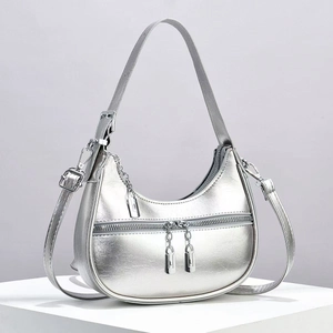 Detail of silver crescent moon shoulder bag featuring smooth metallic finish and zip pocket