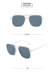 Detail of white glossy aviator sunglasses with gold studs and grey lenses