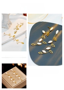 Detailed view of long gold leaf earrings with white pearls and elegant vine design