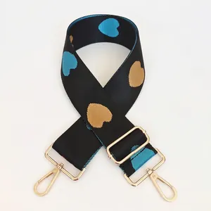 Adjustable black nylon bag strap with blue and gold jacquard heart pattern and gold hooks