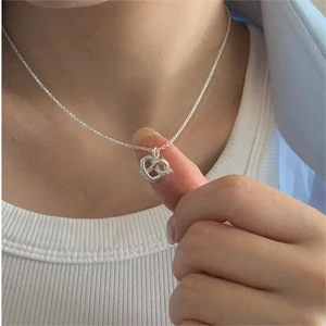 Macro shot of 925 sterling silver twisted heart pendant necklace on a delicate chain