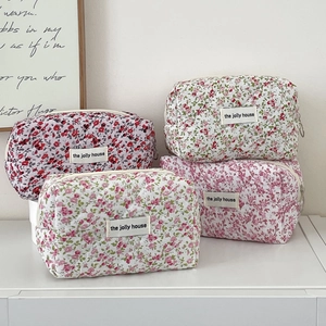 Detail of four quilted floral toiletry bags showing cotton texture and top zipper