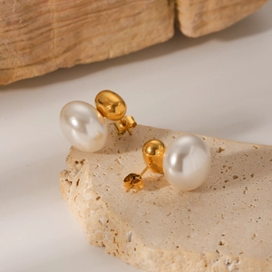 Close-up of vintage pearl earrings on a stone base with elegant gold plating details