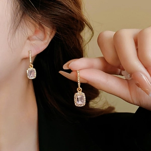 Nahaufnahme der rosa rechteckigen Kristallohrringe mit kleinen weißen Diamanten auf Gold