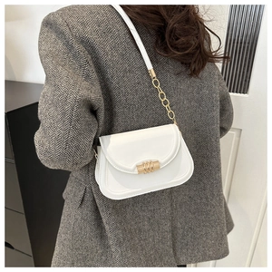 Side view of a white crossbody bag with gold chain strap on a brown blazer outfit