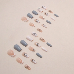 Short coffin press-on nails with grey and nude tones, featuring stars and smiley faces
