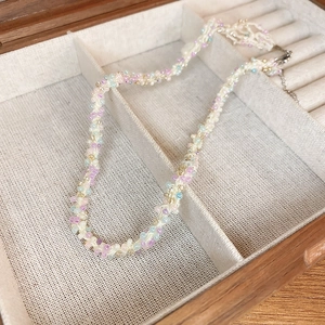 Détail d'un collier en perles pastel avec fermoir argenté dans une boîte à bijoux