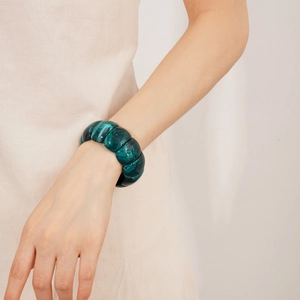 Close-up of chunky dark green acrylic geometric bracelet with marble texture on wrist