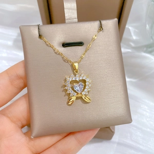Close-up of golden bow heart necklace with sparkling crystals in a luxury jewelry box