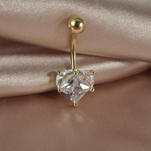 Golden heart zircon belly ring on silk fabric background with professional lighting