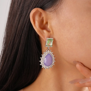 Close-up of vintage drop earrings with purple pear-shaped stone and green crystals
