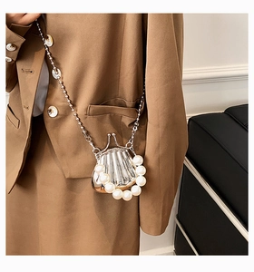 Detail einer Mini-Umhängetasche in Silbermuschelform mit Perlenbesatz und kleiner Kette