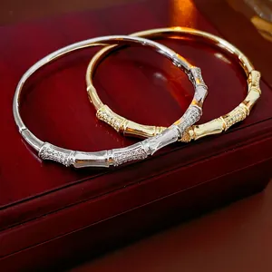 Bamboo style gold and silver bangles with pavé zircon stones on a wooden jewelry box