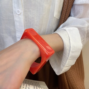 Close-up of bright orange square acrylic resin bangle with smooth glossy finish