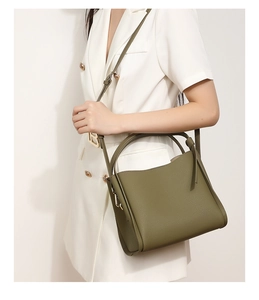 Olive green lychee pattern leather bucket bag shown being carried by a model in a white suit
