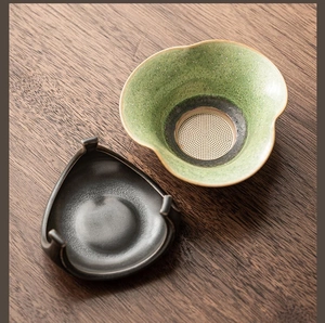 Detail of green petal-shaped ceramic tea strainer with black triangular stand base
