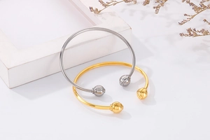 Detailed view of minimalist gold and silver bead open bangles on a modern artistic display