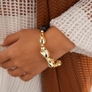 Détail du bracelet de perles géométriques avec accent en métal doré sur le poignet