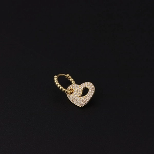 Detailed macro view of a heart-shaped gold earring with micro-paved white zircon stones
