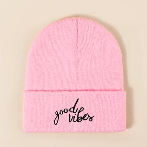 Pink Good Vibes knitted beanie hat with black embroidery on a beige background