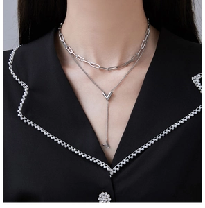 Detailed close-up of double-layered silver V-shaped pendant necklace with long tassel design