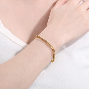 Close-up of a golden stainless steel wheat chain bracelet worn on a wrist for men and women