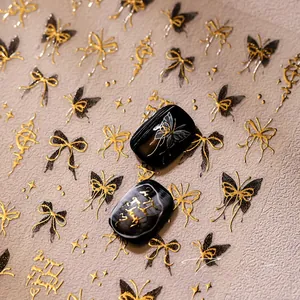 Détail de stickers nail art 3D gaufrés papillon et nœud doré sur ongles noirs