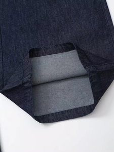 Gros plan des doubles coutures sur un pantalon en jean bleu foncé montrant le tissu