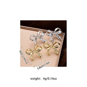 Detail view of gold and silver bow stud earrings showing precise size and weight specs