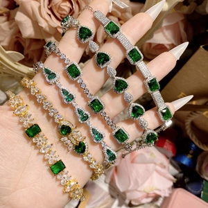 Close-up of vintage gold and silver bracelets with green spinel and floral accents