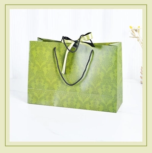 Detail of luxury green gift paper bag with vintage pattern and black ribbon bow handle