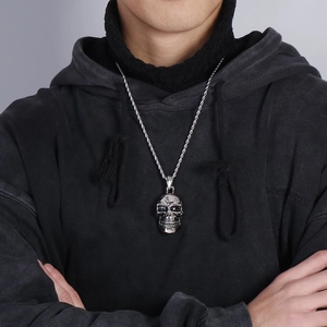Close-up of a silver skull pendant with twist chain worn by a male model in casual attire