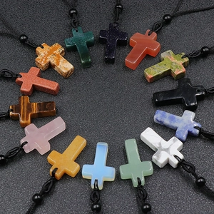 Set of natural crystal cross pendants with woven cords on a dark textured surface