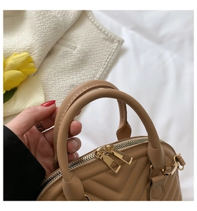 Detail of beige quilted leather handbag with golden dual zippers and sturdy top handles