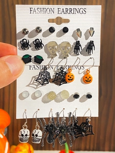 Macro detail of Halloween earring set featuring spider, skull, and pumpkin charms
