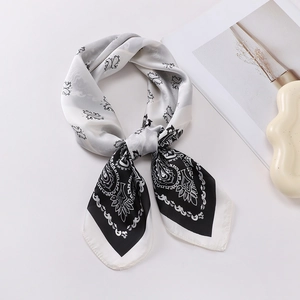 Close-up of a knotted black and white paisley silk scarf with a soft satin finish texture