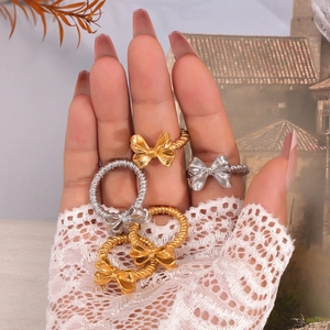 Eleganti anelli a fiocco in oro e argento presentati su una mano con guanti di pizzo