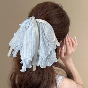 Elegant light blue pleated mesh bow hair clip with pearl detail shown on a model