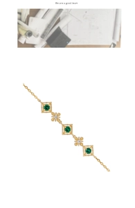 Nahaufnahme eines Vintage-Goldarmbands mit grünen Smaragden und hohlen Basteldetails