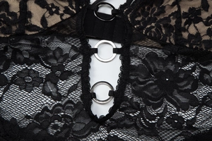 Detail aus floraler schwarzer Spitze mit silbernen Metallringen an einem Kleid