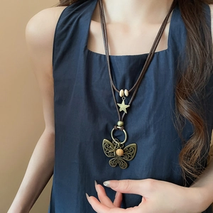 Detail of vintage necklace with hollow butterfly pendant and wood beads on a wax cord