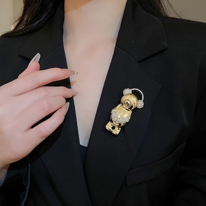 Detail of a sparkling gold bear brooch with crystal headphones on black suit lapel