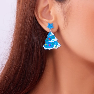 Close-up of a blue glitter Christmas tree earring with star detail on a female model