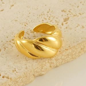 Detail shot of a textured gold-plated braided croissant ring on a stone surface