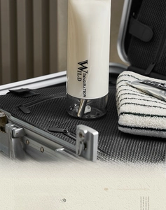 Detail of minimalist portable travel toiletry bottle stored inside a sleek metal suitcase
