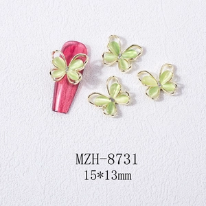 Macro shot of green cat eye stone butterfly nail art charms with golden edges and rhinestones