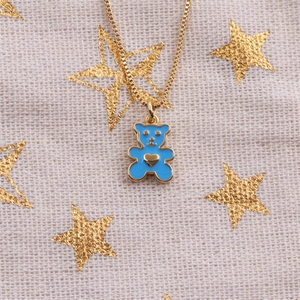 Détail d'un collier pendentif ours bleu avec cœur doré et confettis d'étoiles
