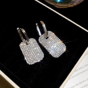 Dettaglio degli orecchini a U in argento con pendenti rettangolari diamantati su velluto