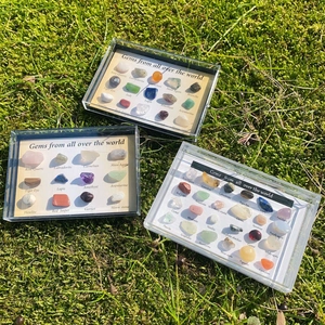 Polished natural crystal specimens in collector boxes on a mossy green background